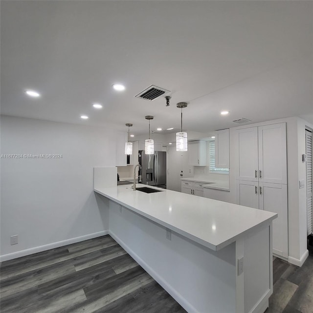 kitchen featuring kitchen peninsula, hanging light fixtures, white cabinetry, dark wood-type flooring, and stainless steel refrigerator with ice dispenser