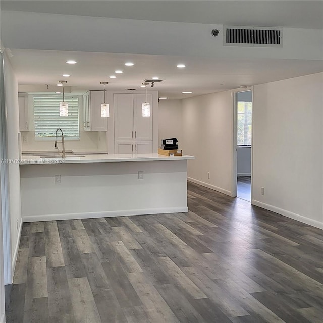 kitchen with sink, decorative light fixtures, dark hardwood / wood-style floors, and a breakfast bar