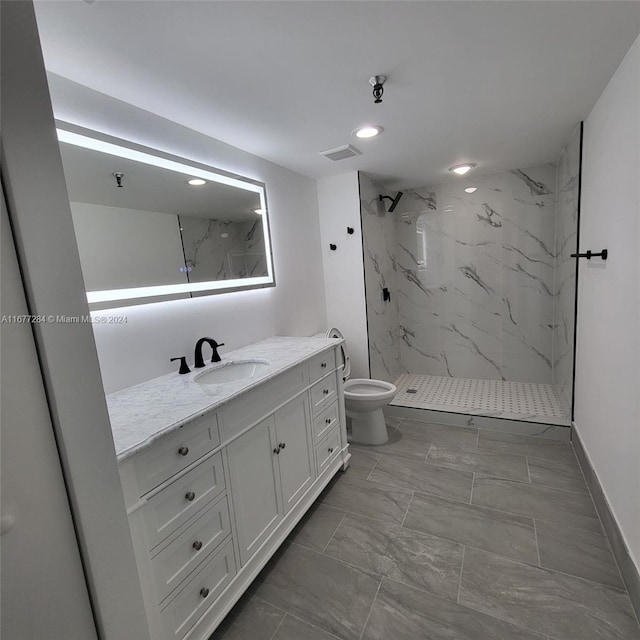 bathroom with vanity, toilet, and a tile shower