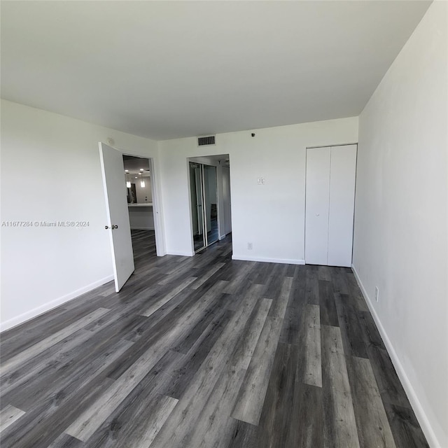 unfurnished bedroom featuring dark wood-type flooring and a closet