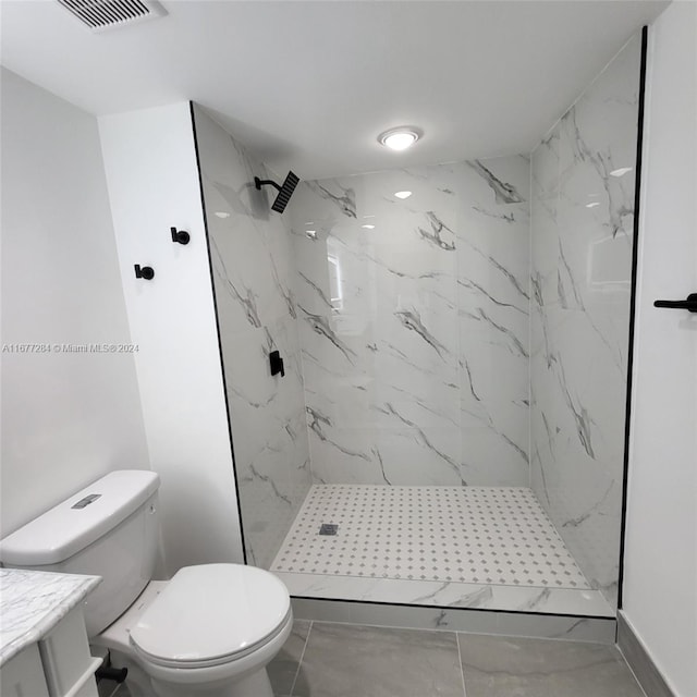 bathroom featuring vanity, toilet, and a tile shower