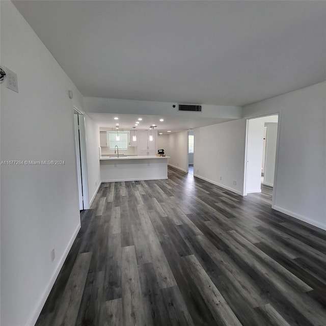 unfurnished living room featuring sink and dark hardwood / wood-style flooring