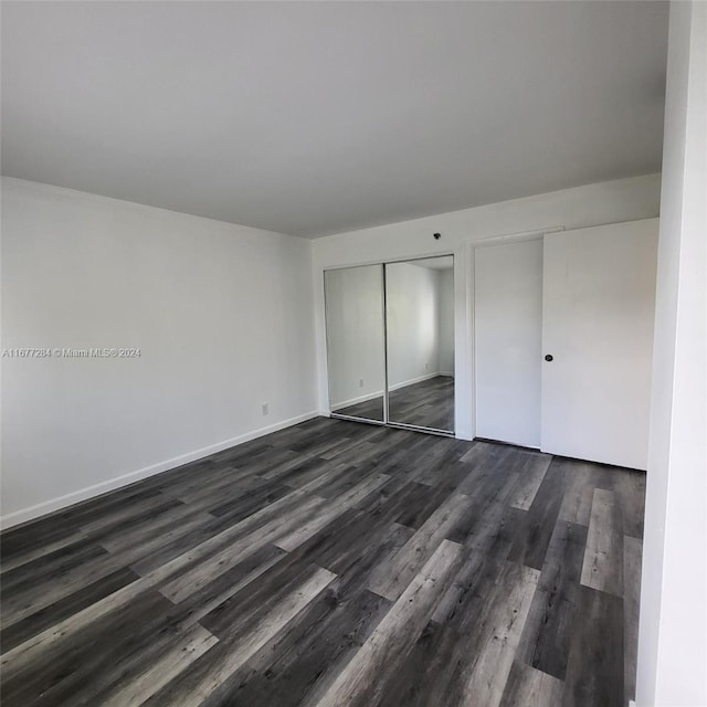 unfurnished bedroom with dark hardwood / wood-style flooring