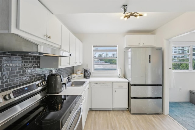 kitchen with appliances with stainless steel finishes, sink, light wood-type flooring, white cabinetry, and decorative backsplash