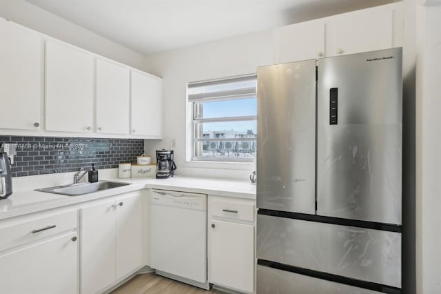 kitchen featuring sink, white dishwasher, stainless steel fridge, light hardwood / wood-style floors, and white cabinets