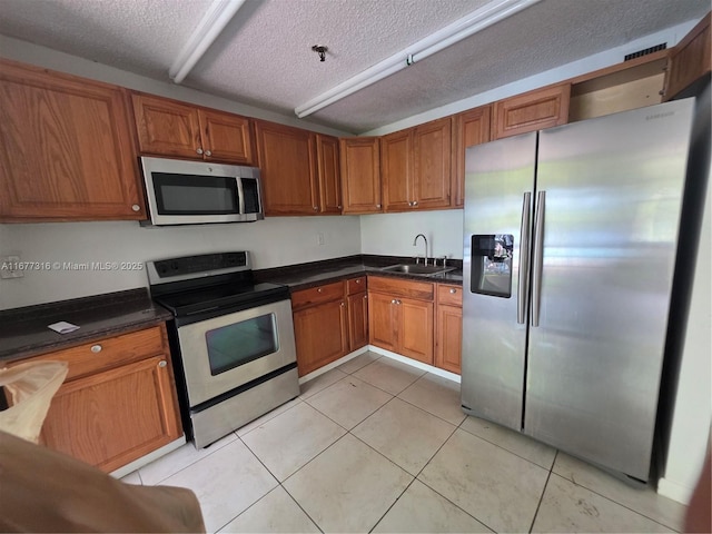 661 NE 195th St Unit 215, Miami, FL 33179 - kitchen featuring stainless steel appliances, brown cabinetry, a textured ceiling, and dark countertops