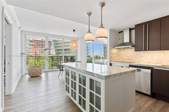 kitchen with wall chimney range hood, light hardwood / wood-style flooring, dark brown cabinets, a center island, and stainless steel dishwasher