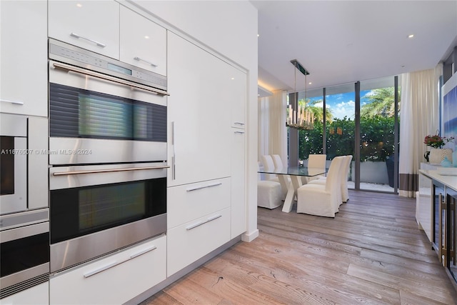 9501 Collins Ave Unit Th1, Surfside, FL 33154 - kitchen with stainless steel double oven, modern cabinets, white cabinetry, expansive windows, and light wood finished floors