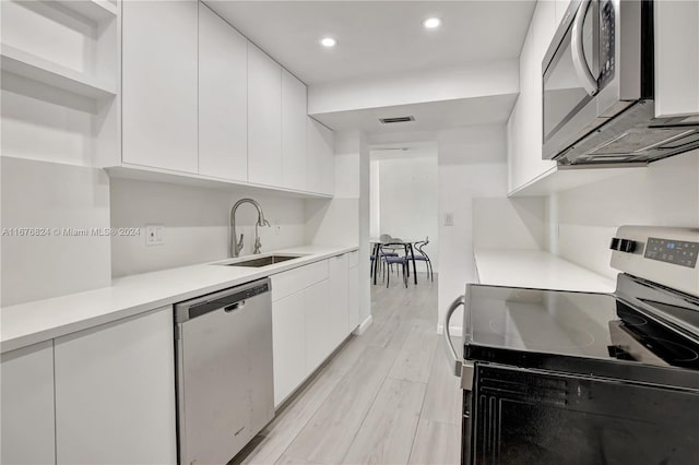 kitchen featuring sink, appliances with stainless steel finishes, white cabinetry, and light hardwood / wood-style floors