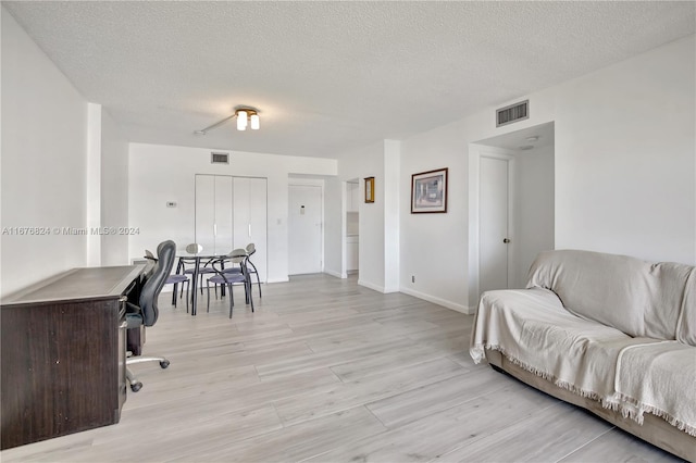 office area with a textured ceiling and light hardwood / wood-style flooring