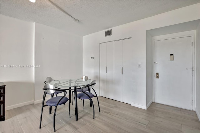 dining area featuring light hardwood / wood-style flooring and a textured ceiling