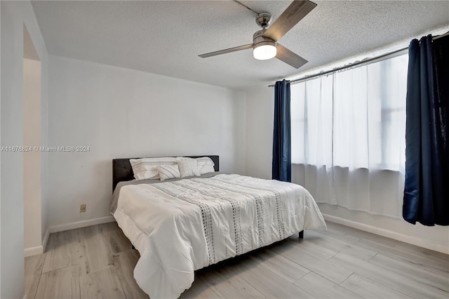 bedroom featuring a textured ceiling, light wood-type flooring, and ceiling fan