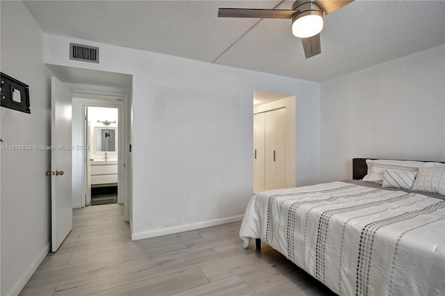 bedroom featuring light hardwood / wood-style floors, a textured ceiling, and ceiling fan