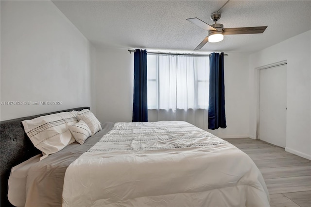 bedroom with ceiling fan, a textured ceiling, and light hardwood / wood-style flooring