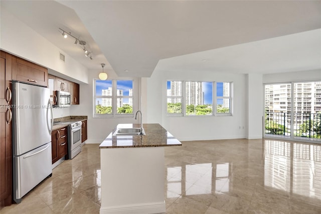 kitchen with sink, appliances with stainless steel finishes, a healthy amount of sunlight, and dark stone countertops