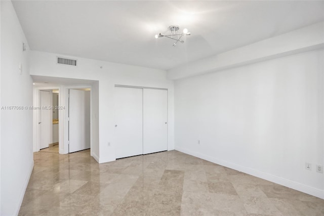 unfurnished bedroom with an inviting chandelier and a closet