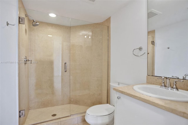 bathroom with a shower with door, vanity, toilet, and tile patterned floors