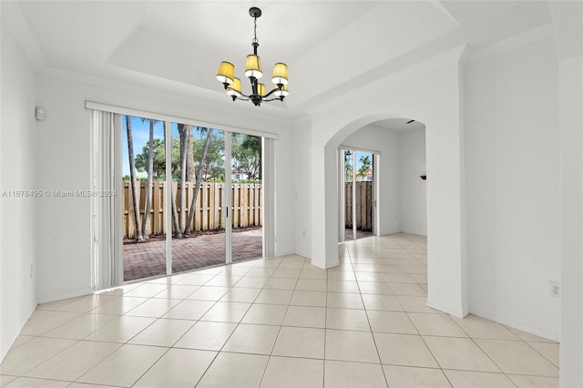 spare room featuring an inviting chandelier, light tile patterned flooring, crown molding, and a tray ceiling