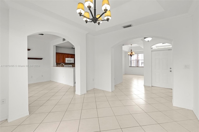 tiled empty room with a notable chandelier, a raised ceiling, and crown molding