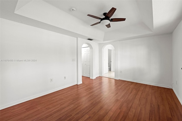 unfurnished room with hardwood / wood-style flooring, a raised ceiling, and ceiling fan