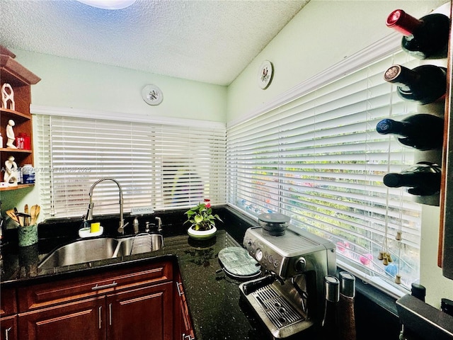 kitchen featuring a textured ceiling, dark stone countertops, and sink