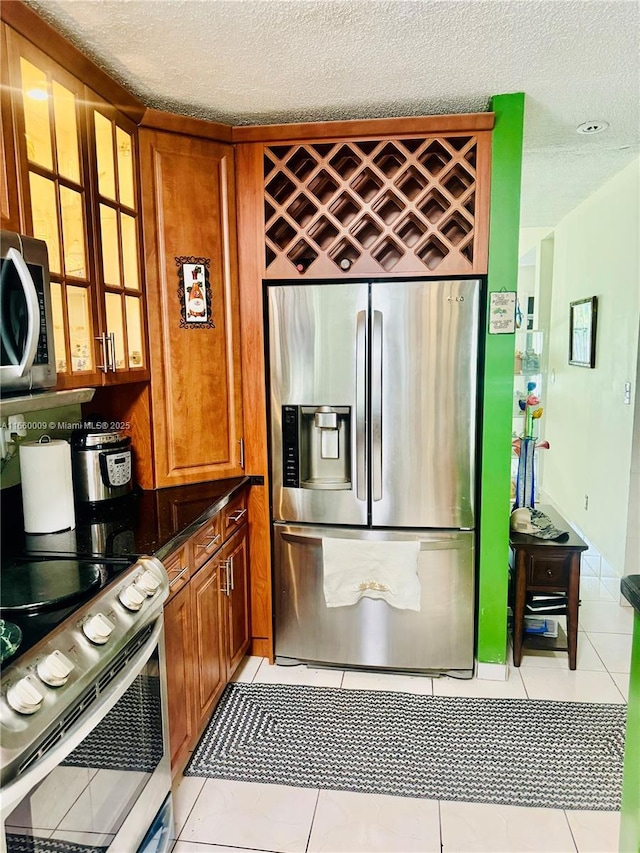 kitchen with appliances with stainless steel finishes, a textured ceiling, and light tile patterned flooring