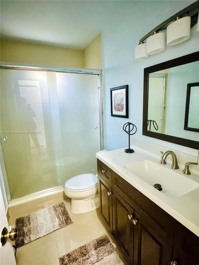 bathroom with tile patterned floors, vanity, an enclosed shower, and toilet