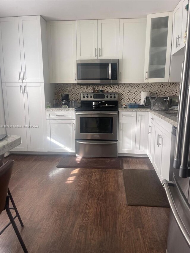 kitchen featuring appliances with stainless steel finishes, light stone counters, white cabinetry, and tasteful backsplash