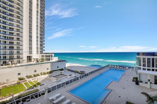 view of pool with a patio area, a water view, and a beach view