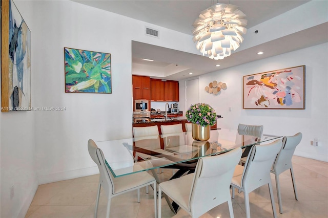 dining space featuring an inviting chandelier, light tile patterned floors, and a raised ceiling