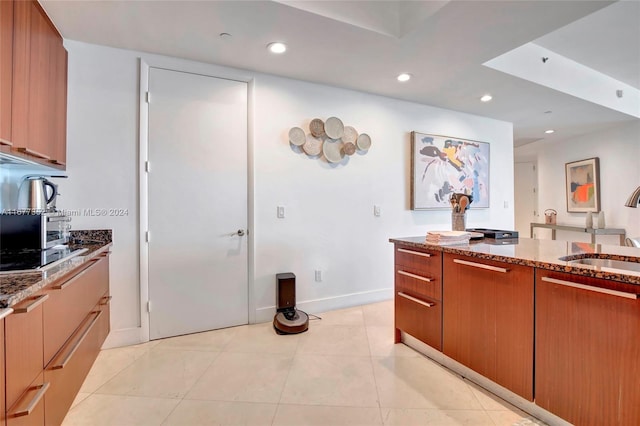 kitchen with sink, light tile patterned floors, and dark stone countertops