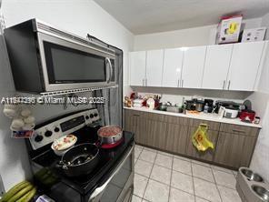 kitchen featuring light tile patterned flooring, white cabinets, and appliances with stainless steel finishes