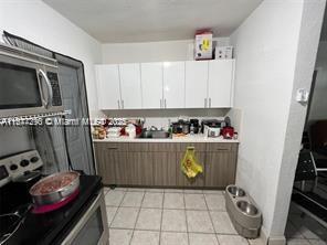 kitchen with appliances with stainless steel finishes, white cabinetry, and light tile patterned floors