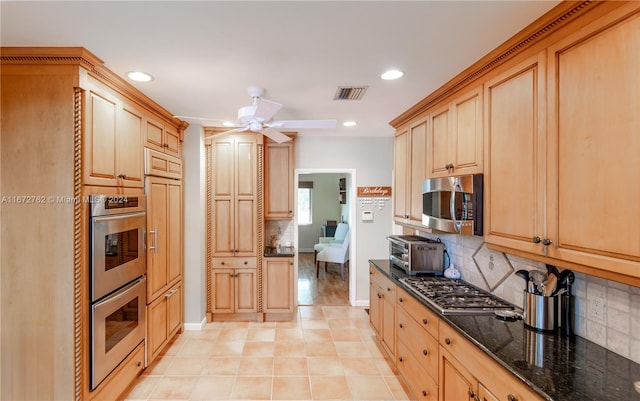 kitchen featuring light brown cabinets, decorative backsplash, ceiling fan, dark stone countertops, and stainless steel appliances