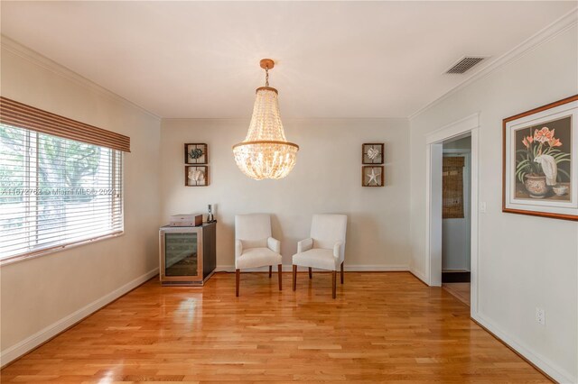 living area featuring crown molding, a notable chandelier, and light hardwood / wood-style floors