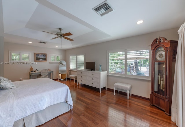 bedroom featuring dark hardwood / wood-style floors, a tray ceiling, and ceiling fan