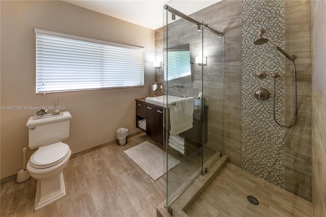 bathroom featuring toilet, vanity, and a shower with door