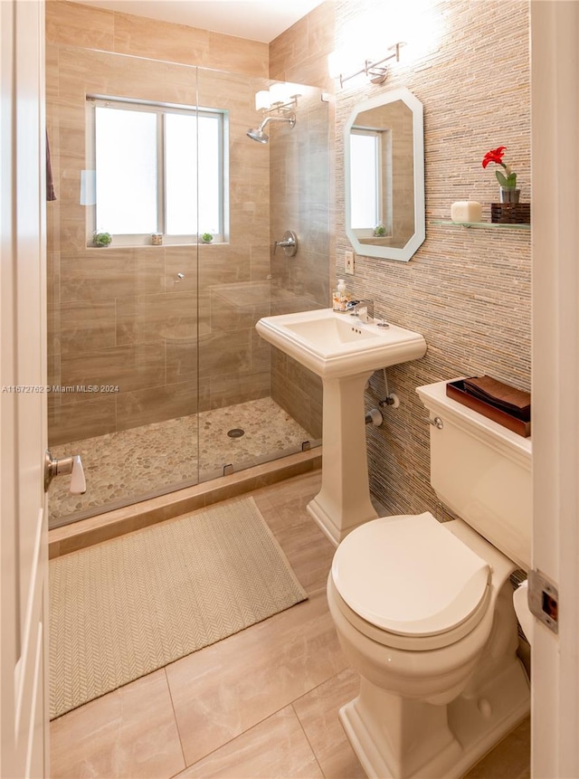 bathroom with tile patterned flooring, toilet, tile walls, and tiled shower