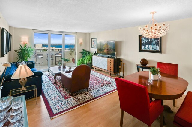 living room featuring wood-type flooring, expansive windows, a textured ceiling, and an inviting chandelier