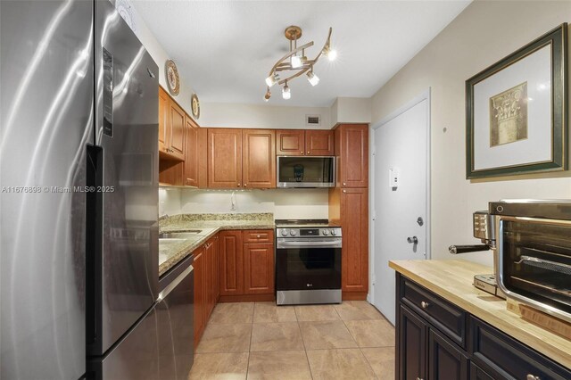 kitchen with light stone counters, stainless steel appliances, and light tile patterned flooring