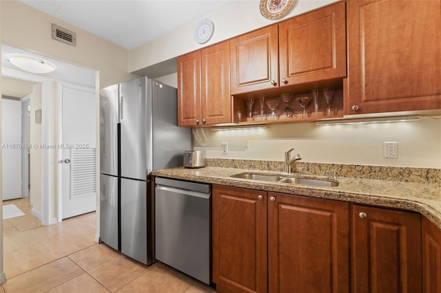 kitchen featuring stainless steel dishwasher, light stone countertops, sink, and light tile patterned flooring