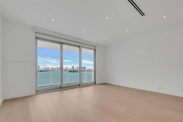 unfurnished room featuring a water view and light wood-type flooring