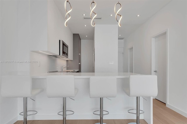 kitchen with appliances with stainless steel finishes, gray cabinets, sink, and light hardwood / wood-style flooring