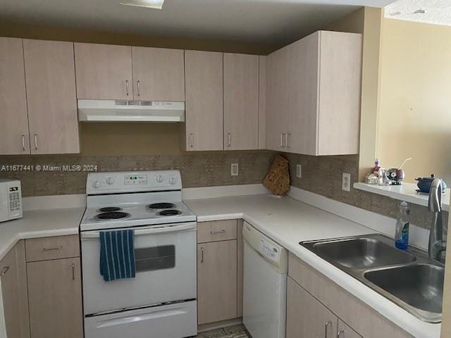 kitchen featuring white appliances, backsplash, light brown cabinetry, and sink