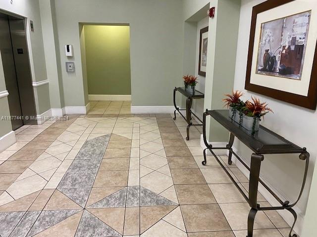50 Menores Ave Unit 829, Coral Gables, FL 33134 - hallway featuring light tile patterned floors, baseboards, and elevator