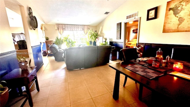 tiled dining area featuring a textured ceiling and lofted ceiling