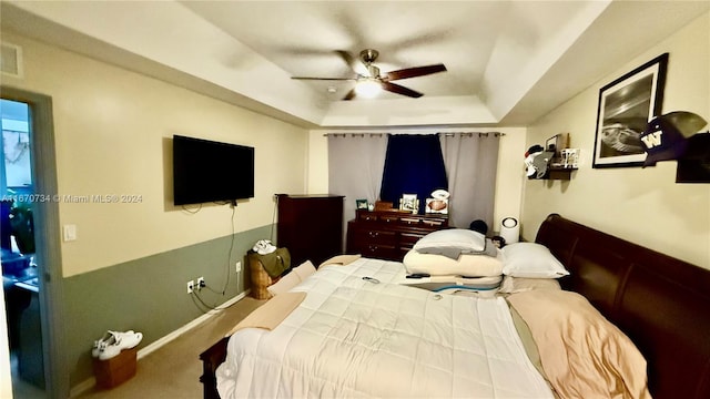 bedroom with a tray ceiling, carpet, and ceiling fan