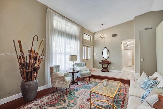 living room featuring high vaulted ceiling, wood-type flooring, and a notable chandelier