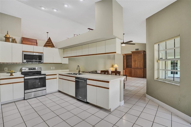 kitchen featuring appliances with stainless steel finishes, light tile patterned floors, sink, white cabinets, and kitchen peninsula