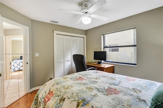 bedroom featuring ceiling fan, a textured ceiling, a closet, and light wood-type flooring